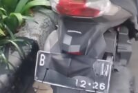 seorang pengendara sepeda motor tertangkap basah oleh petugas saat mencoba menutupi pelat nomor kendaraannya menggunakan masker.