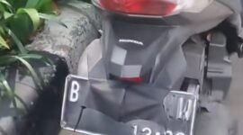 seorang pengendara sepeda motor tertangkap basah oleh petugas saat mencoba menutupi pelat nomor kendaraannya menggunakan masker.