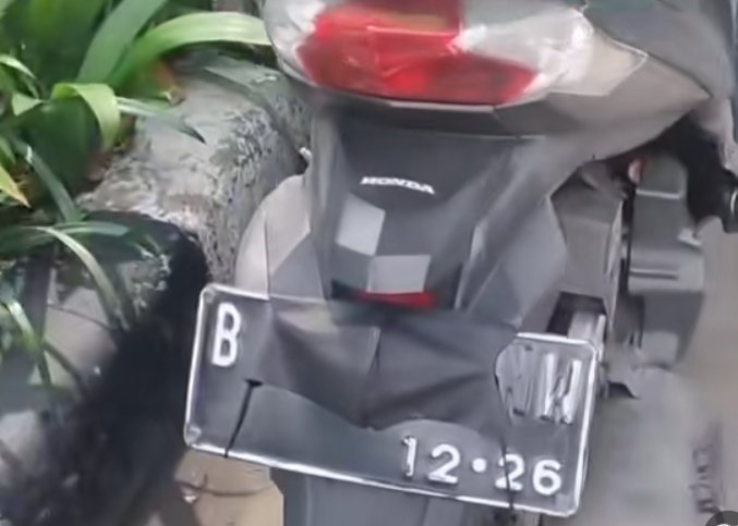 seorang pengendara sepeda motor tertangkap basah oleh petugas saat mencoba menutupi pelat nomor kendaraannya menggunakan masker.